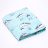 Folded cotton baby swaddle wrap with a whale pattern on a light blue colour.