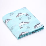 Folded cotton baby swaddle wrap with a whale pattern on a light blue colour.
