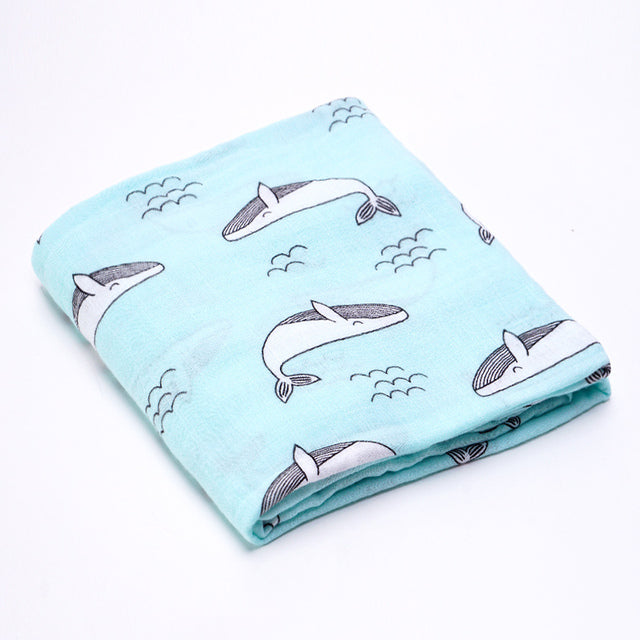 Folded cotton baby swaddle wrap with a whale pattern on a light blue colour.