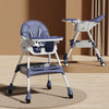 Blue and whitebooster seats high chair with tray on a wooden floor.