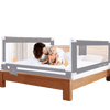 portable toddler bed with a gray safety rail and a baby and woman on the bed.