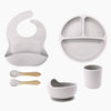 Set of gray baby feeding set including a bib, plate, cup, bowl, and spoons .