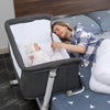 Woman lying next to a baby in a Newborn Baby bedside bassinet .