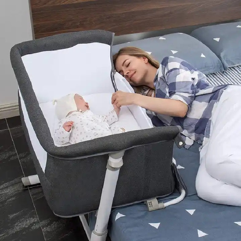 Woman lying next to a baby in a Newborn Baby bedside bassinet .