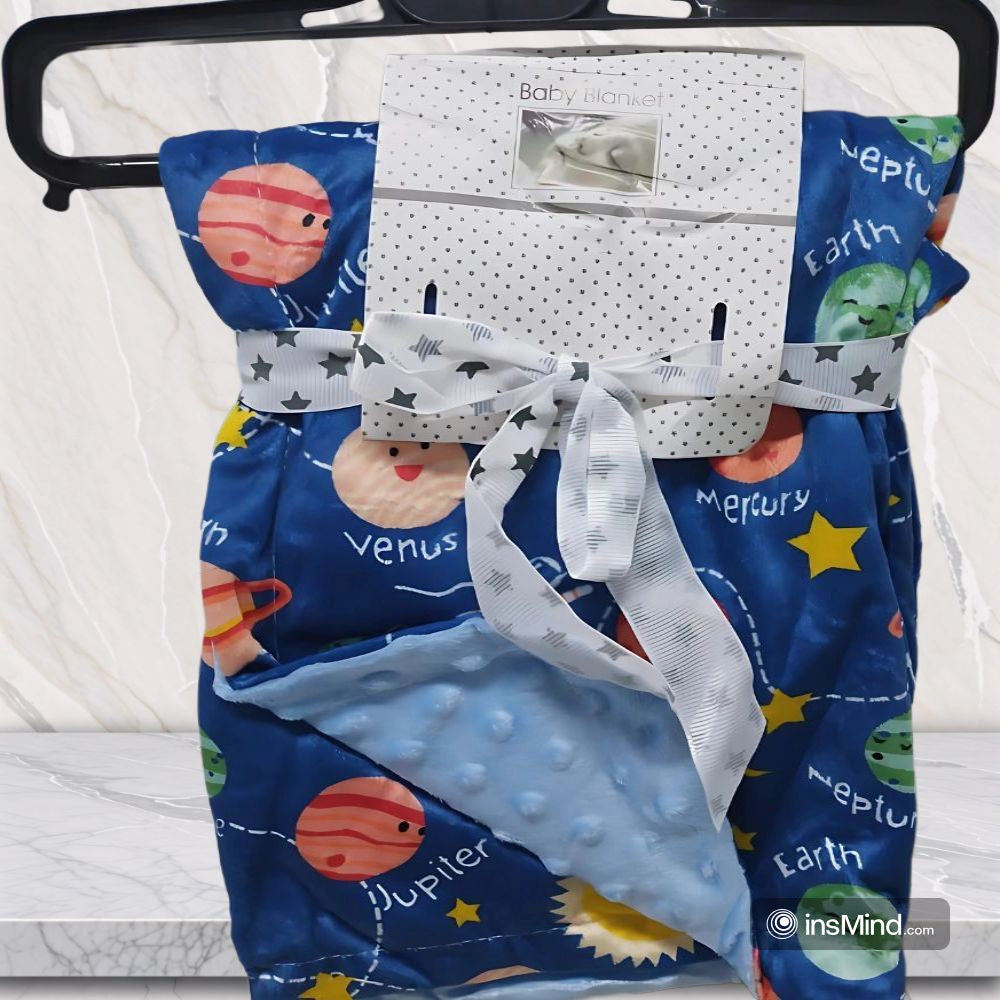 Baby blanket with space-themed design featuring planets and stars, hanging on a black hanger.