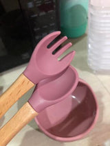 Pink siliconespoon and wooden handle utensils on a kitchen counter.