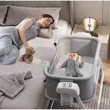 Woman lying on a bed with a baby in a portable baby swing crib .