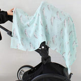Light bluecotton swaddle baby blanket with whale pattern draped over a black stroller.