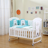 Whitebabycrib with blue and gray bear-themed bedding in a room .