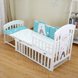 White foldable baby crib with blue and gray bedding in a room .