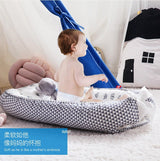 Baby sitting on a geometric-patterned organic breathable baby portable crib
