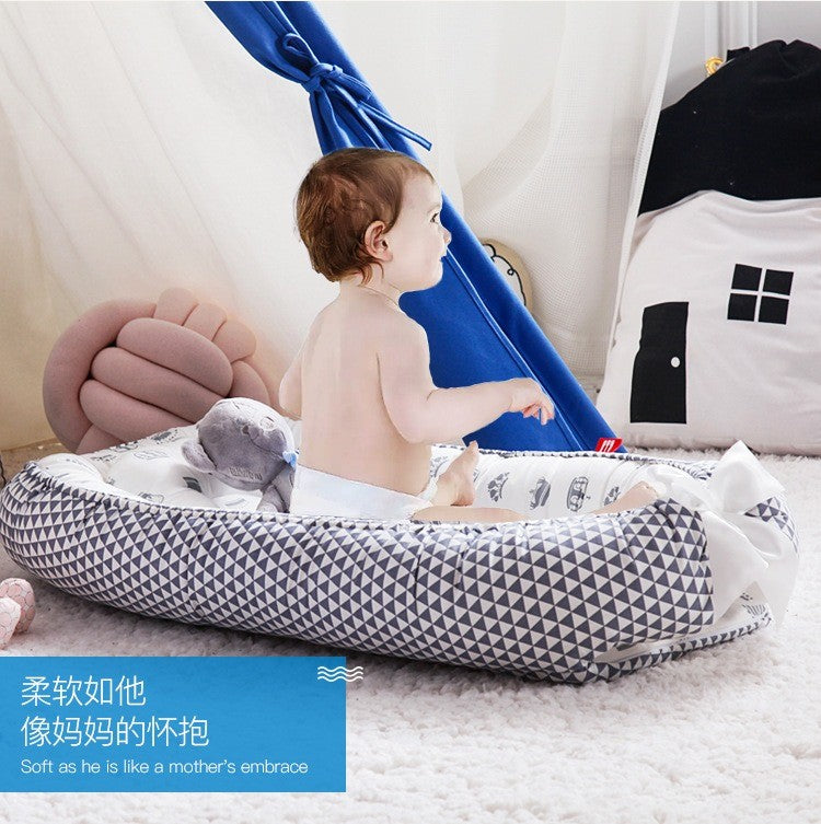 Baby sitting on a geometric-patterned organic breathable baby portable crib
