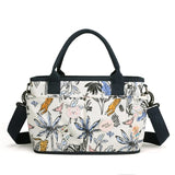 Multicolored floral and animal patterned diaper bag with black straps.