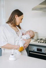 Woman breastfeeding a baby in a double wearable automatic breast pump.