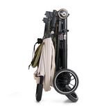 Lightweight foldable baby stroller cart with large black wheels, a light beige fabric cover draped over the frame, and a tan bag hanging from the side handle.