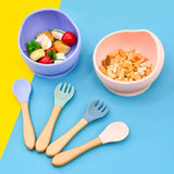  Colorful children's silicone bowls and utensils on a two-tone yellow and blue. 