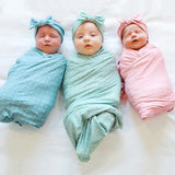 Three babieswith swaddle wrapped blanket and colorful headbands .