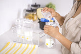 Person pouring milkinto a labeled medela stoarge bags on a kitchen counter.