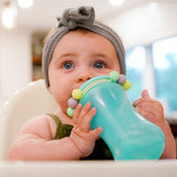 Baby holding a green Melii abacus sippy cup with colorful beads.