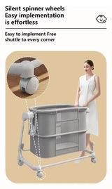 Gray portable baby bassinet with wheels featuring text about silent spinner wheels.
