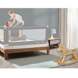 Baby being lifted by a parent over a portable toddler bed with a safety rail.