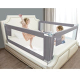 Children playing near a bed with a protable safety protector gate in a room.