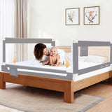 Baby being held by a woman in a bed with a portable toddler safety rail in a bedroom setting.