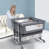 Woman sitting next to a baby in a grayTwin bassinets bedside adjustable crib.