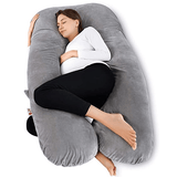 Woman lying on a large U-shaped gray pregnancy pillow .