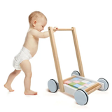 Baby pushing a walkers building blockw toy with colorful blocks on wheels.