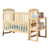 Wooden baby crib with blue mattress and adjacent woodenchanging table .