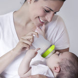 Woman feeding a baby with acomotomo silicone nipple bottle, both wearing white shirts.