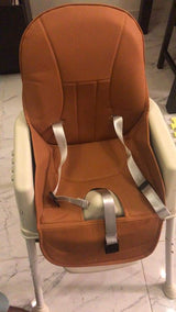 Brown child safety seat secured to a white chair, functioning as a portable dining high chair.