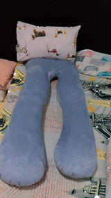 Gray U-shaped body pillow on a bed with a patterned pillow .