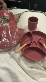 Pink silicone dining set with plate, cup, and utensils .