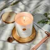 Citrus White Tea candle on a wooden coaster with decorative elements .