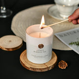 Candle labeled 'Citrus & White Tea' being lit with a match on a dark surface.